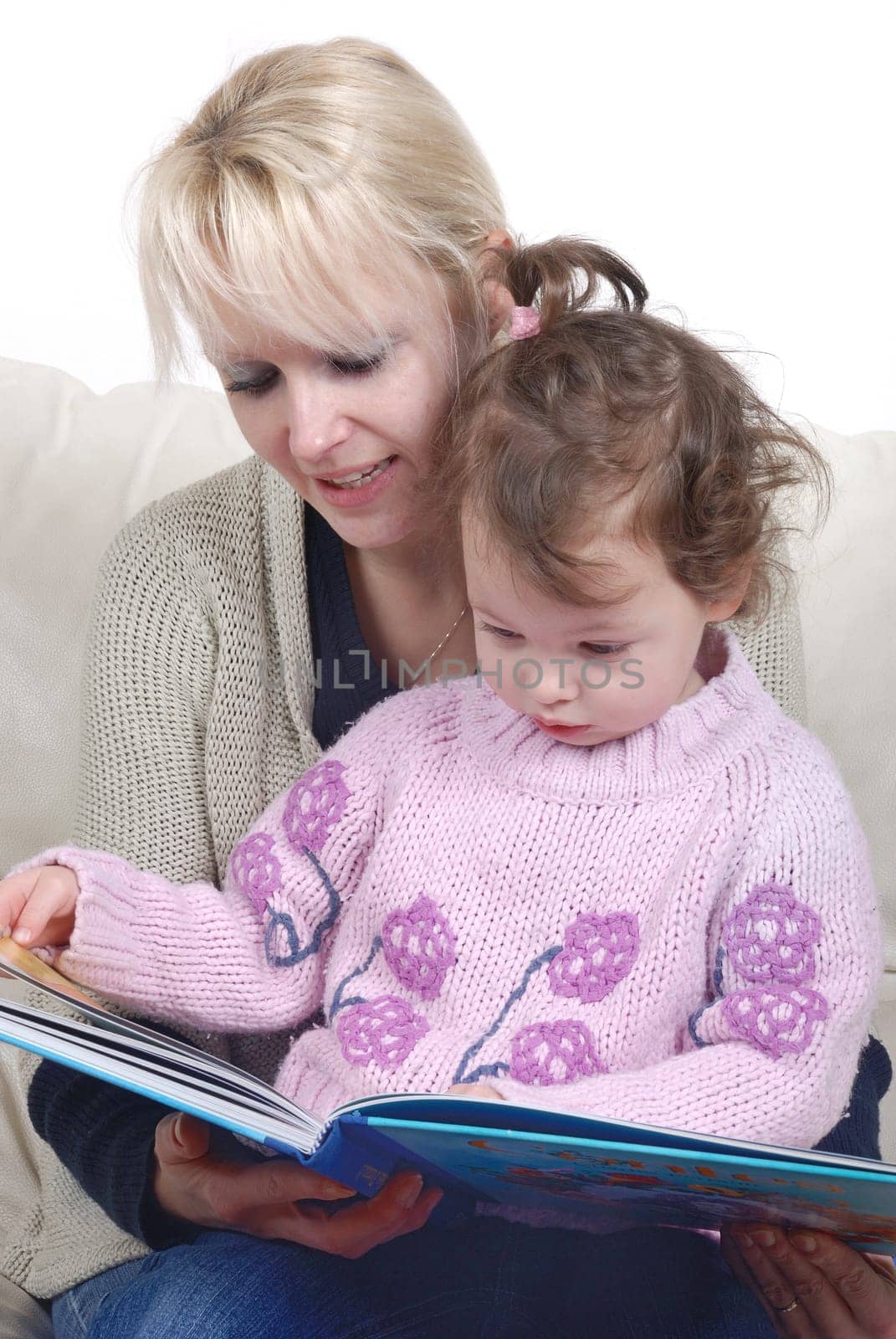 Mother and daughter sitting in living room reading book