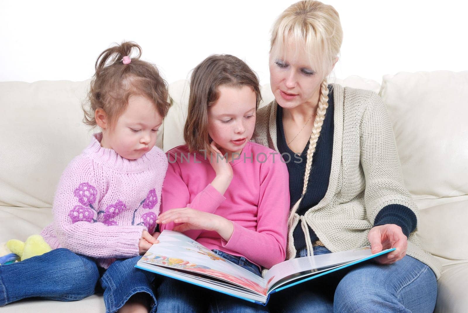 Mother and children sitting in living room reading book