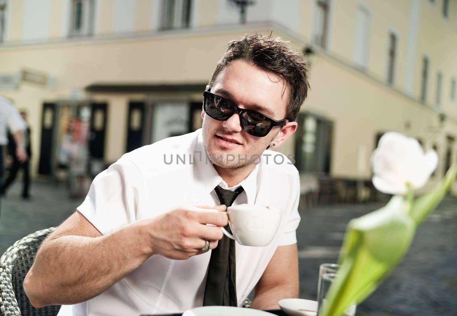 Cool young man drinking coffee in the city