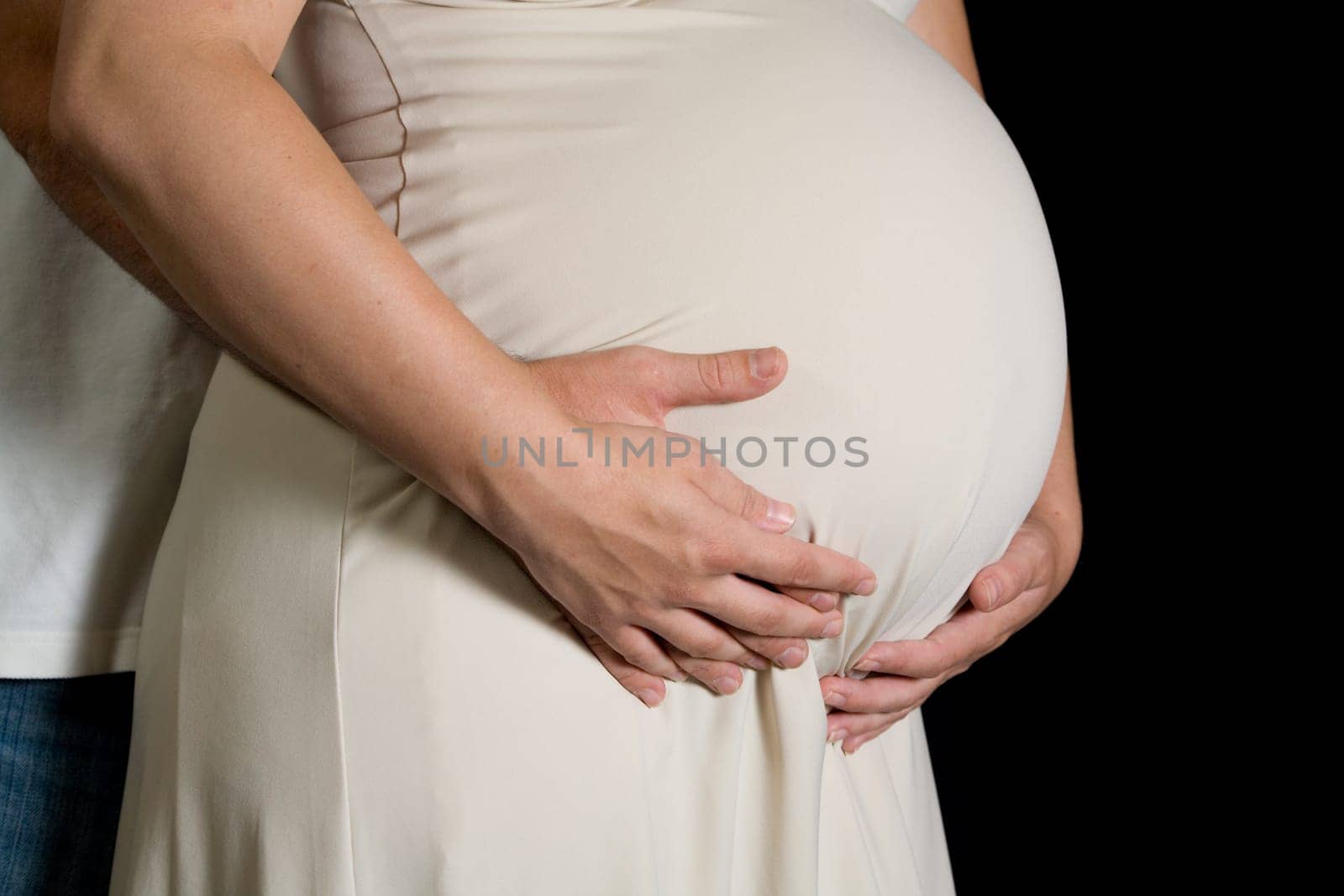A couple is holding their hands on stomach of expectant mother