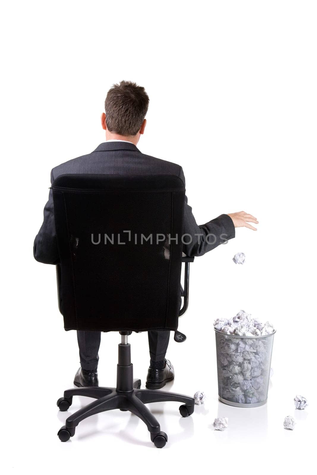 Businessman is throwing another paper ball into already full basket. Isolated on white.