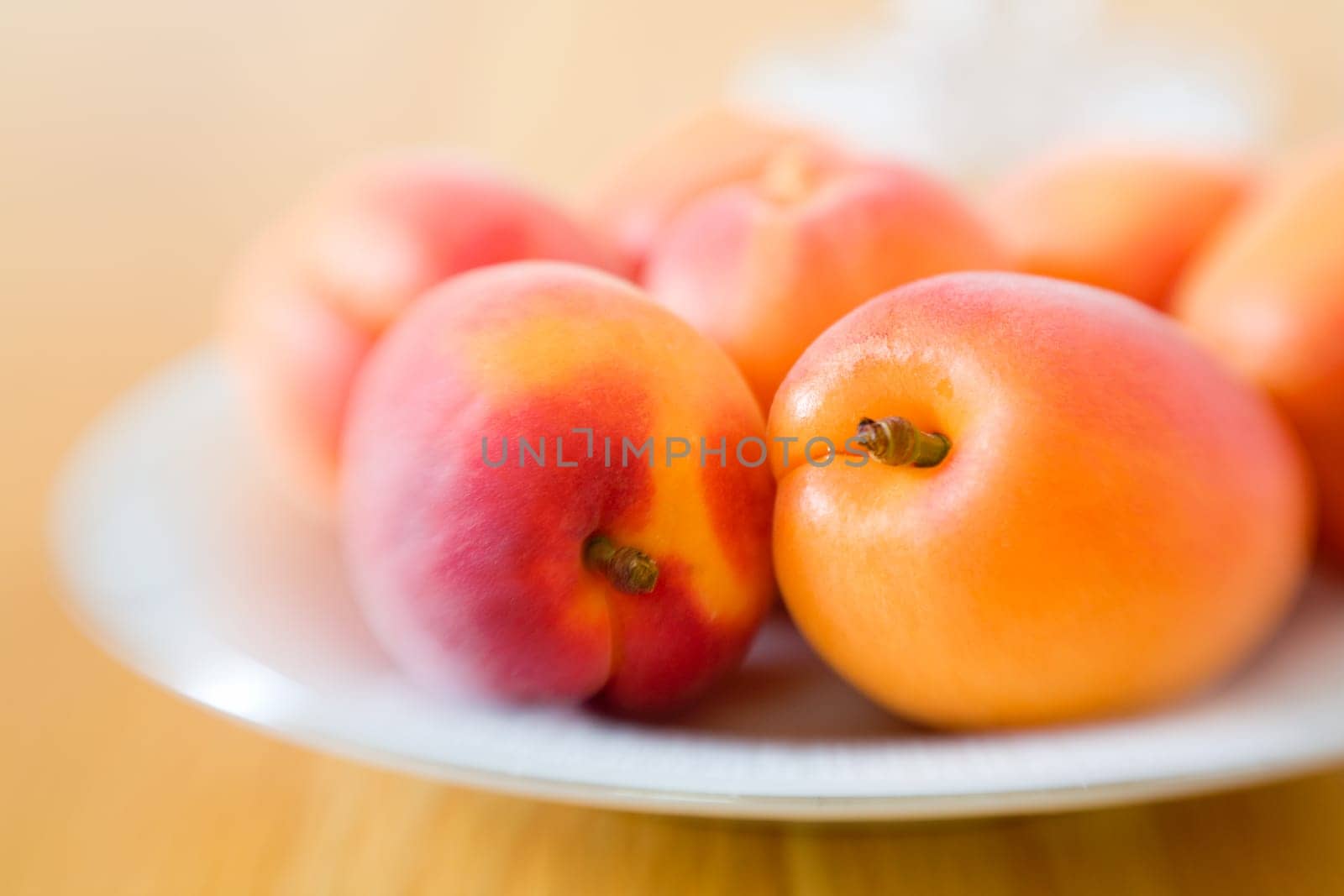 Close-up image of fresh ripe apricots on a plate on dining table. Selective focus by lensbaby
