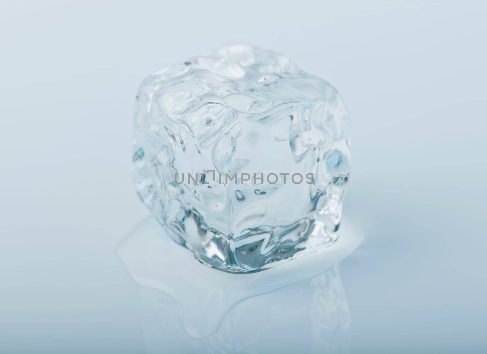 Close-up of an icecube slowly melting away in a puddle of water