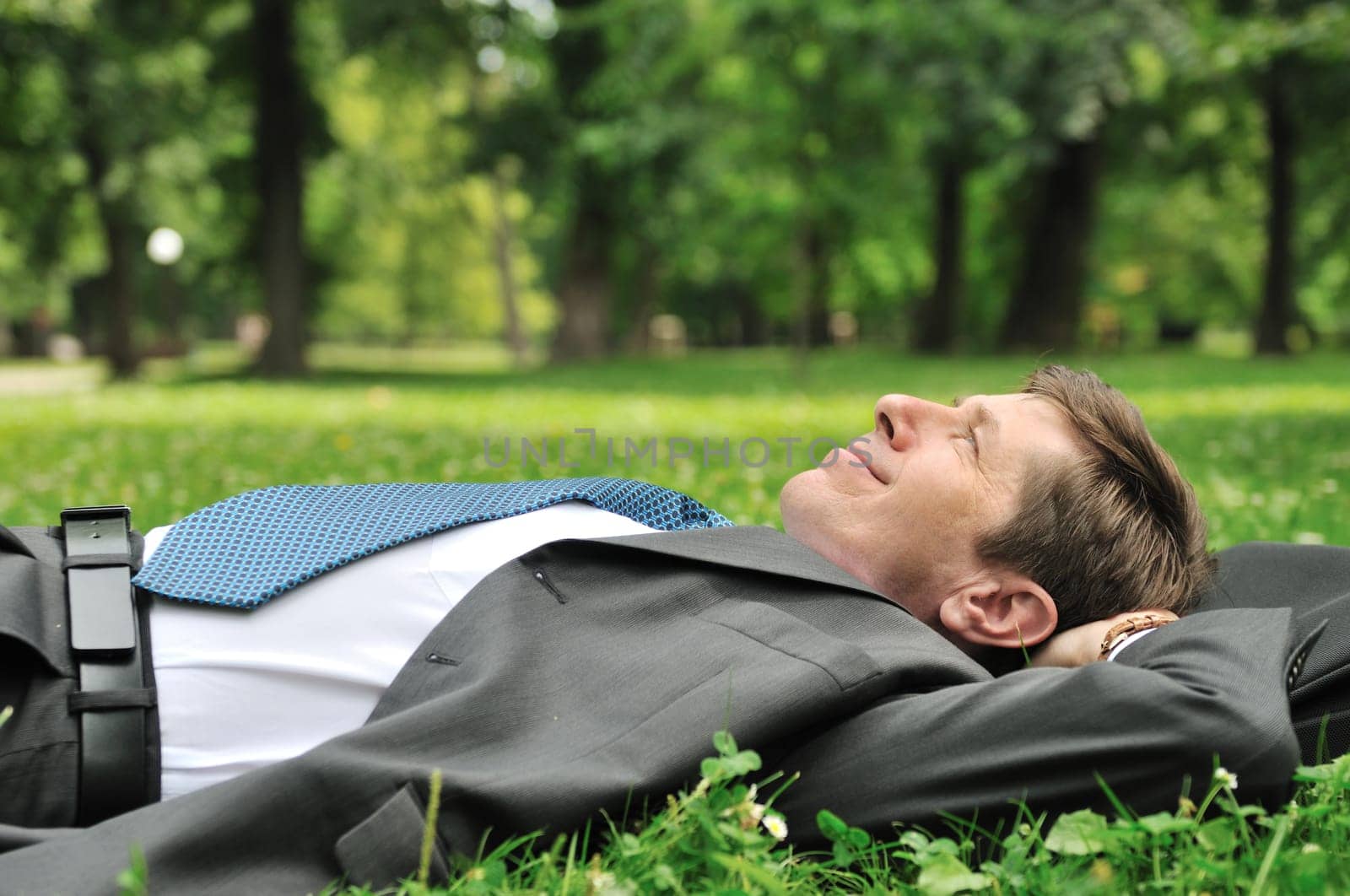 Senior people series - mature business man lying on grass and relaxing in park