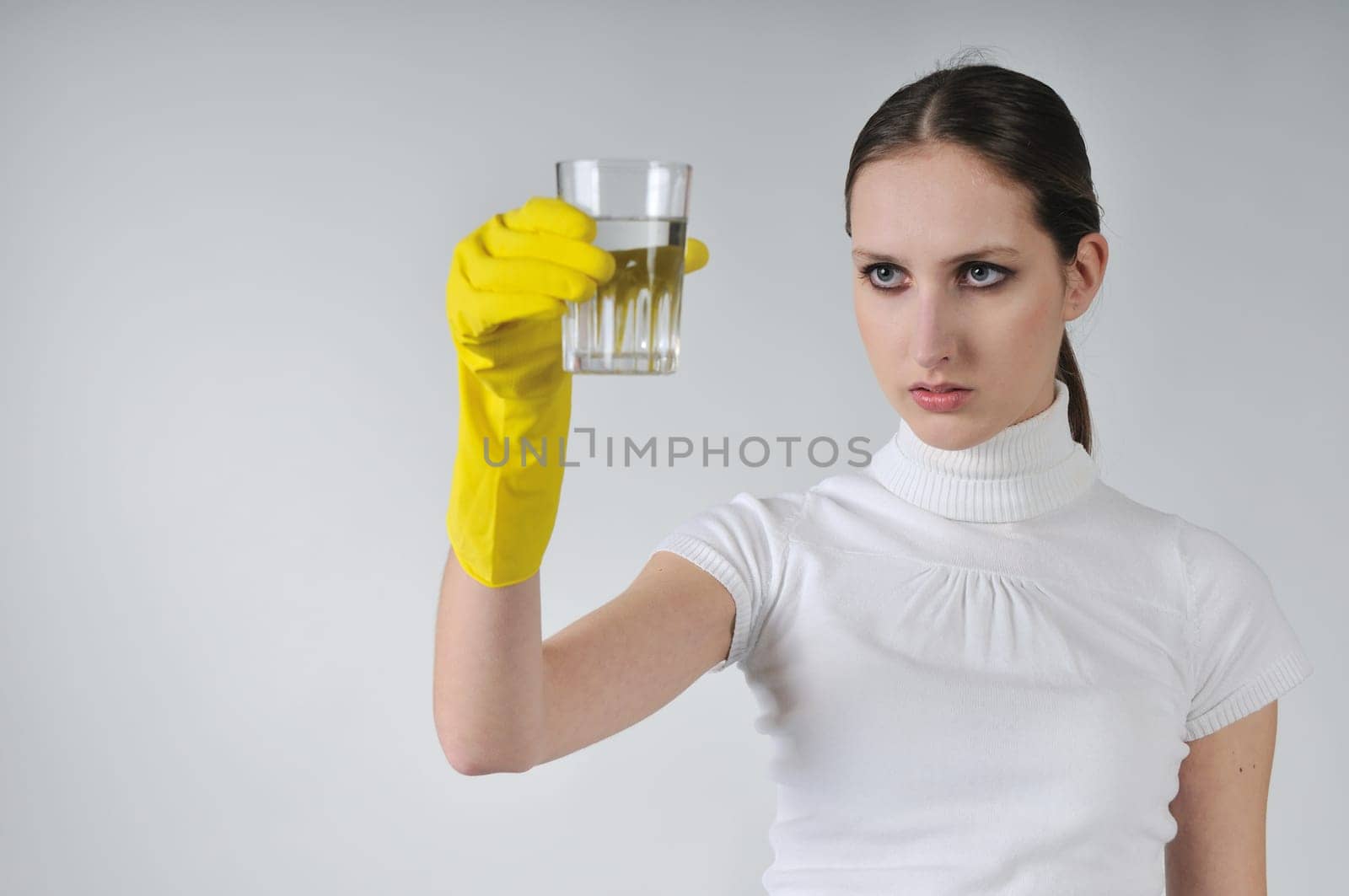 Young woman in yellow hygienic gloves holding glass of water - concentration