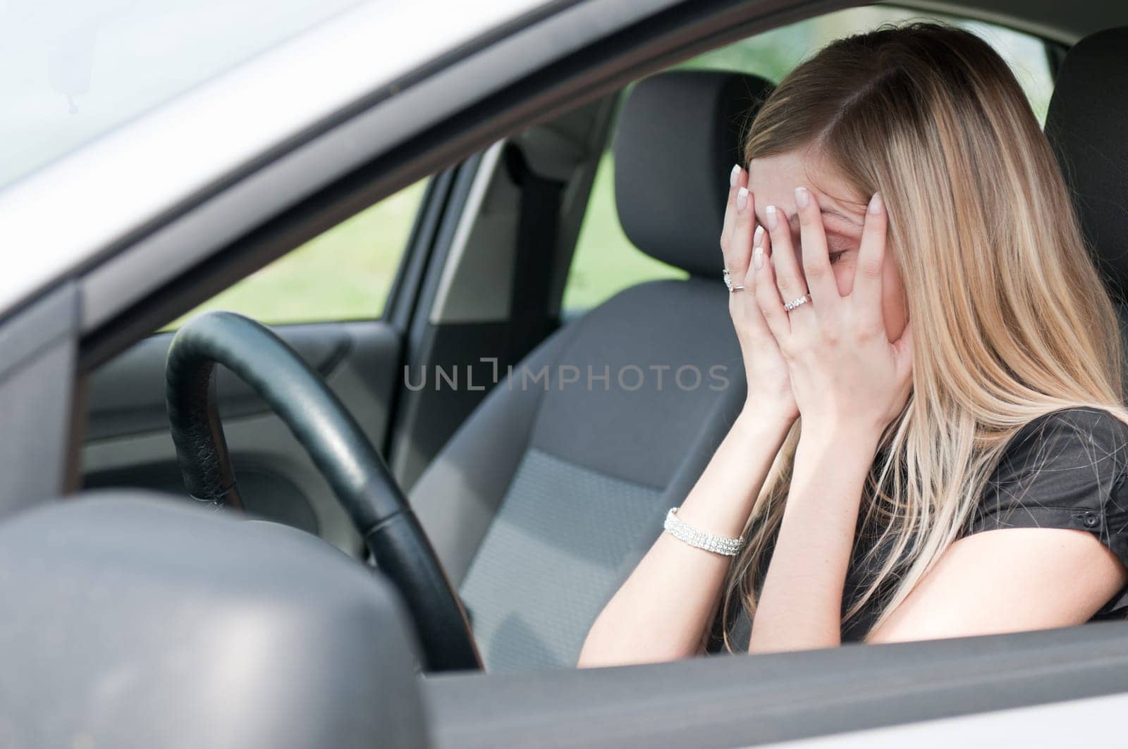 Young woman with hands on eyes sitting depressed in car