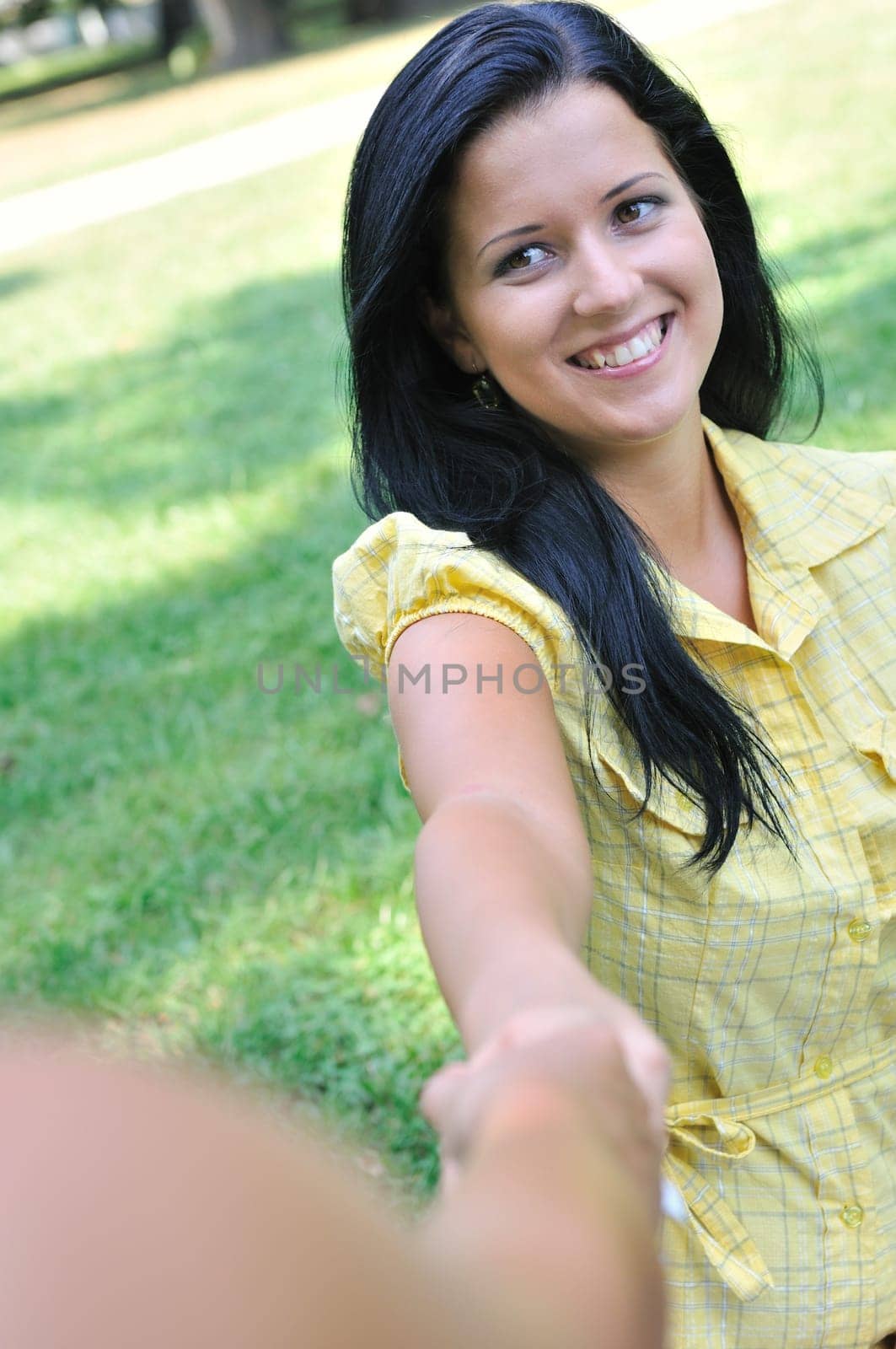 Young smiling woman stretching her hand and receiveing help