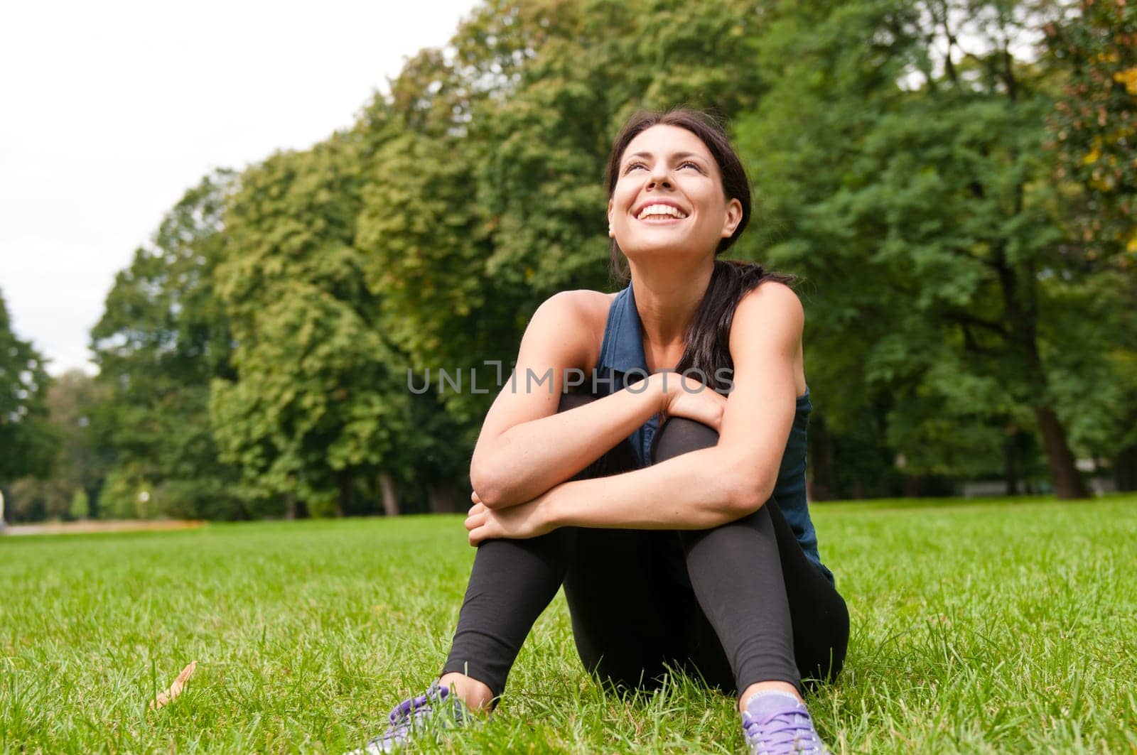 Young happy smiling woman looking up siting in grass