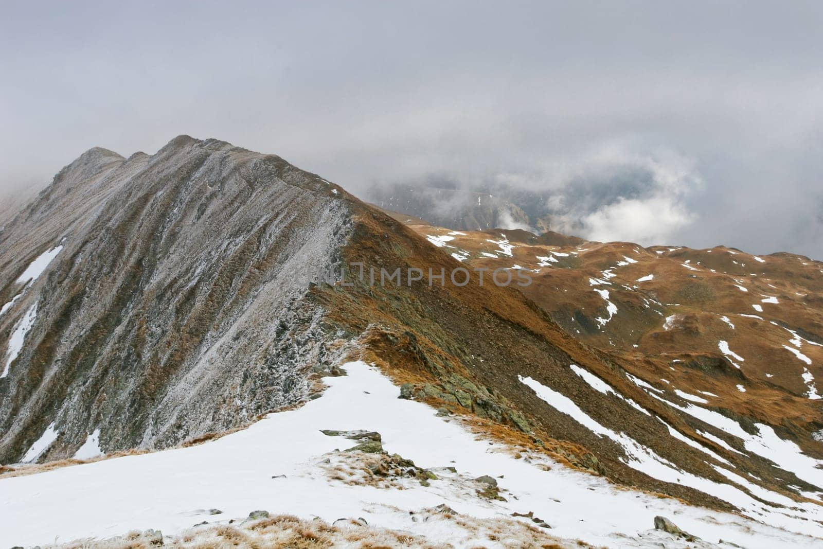 traces of snow on a mountain in clouds