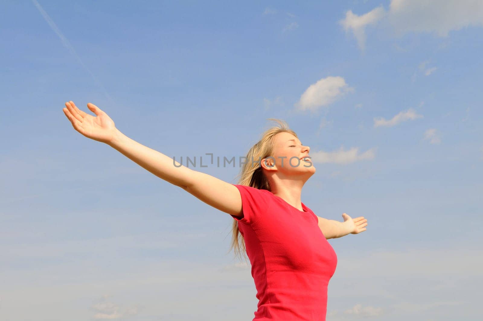 Happy young woman spreads her arms