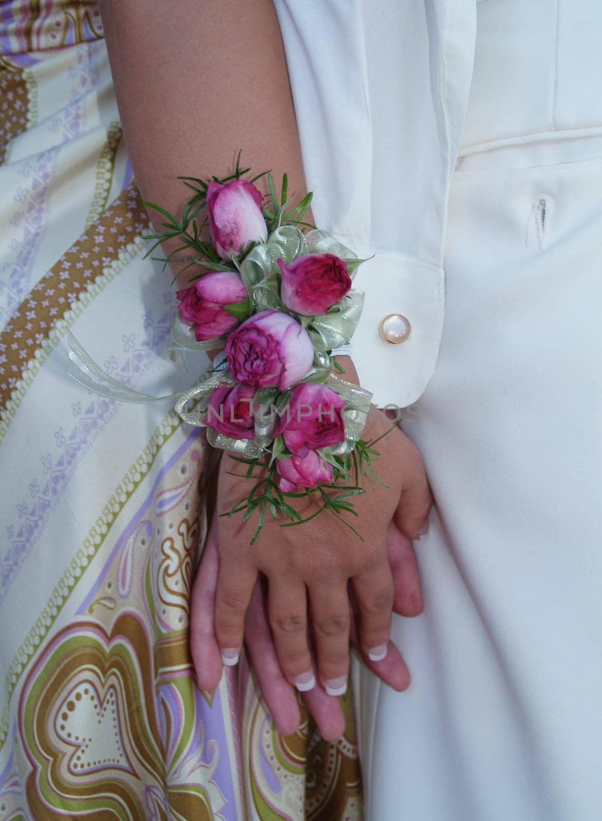 Pink rose wrist corsage with babies breath and green and white ribbons.