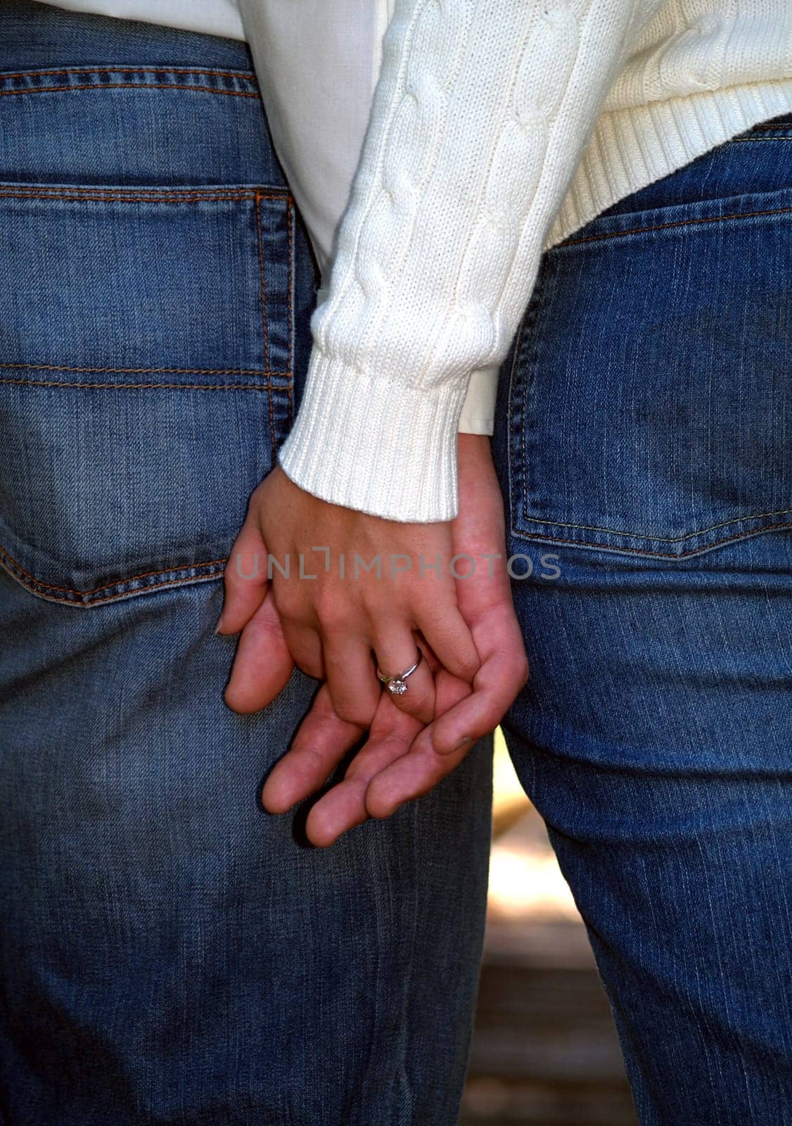 Couple holding hands showing off her engagement ring.