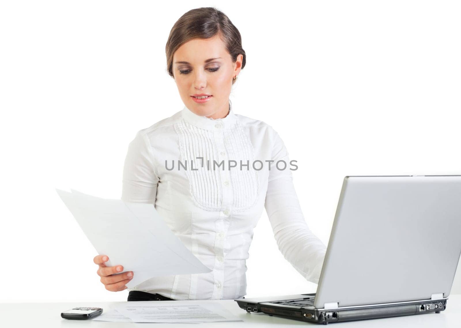 Pretty young businesswoman reading papers at her workplace
