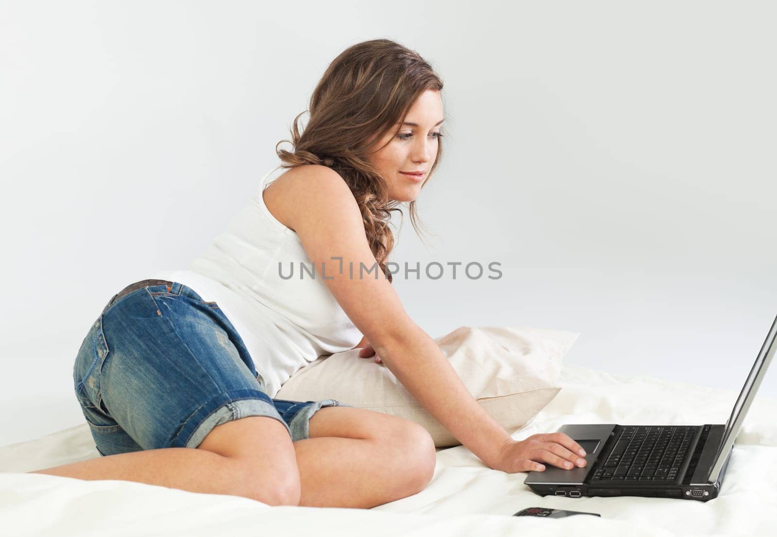 Pretty young woman her bed with laptop computer and cellphone