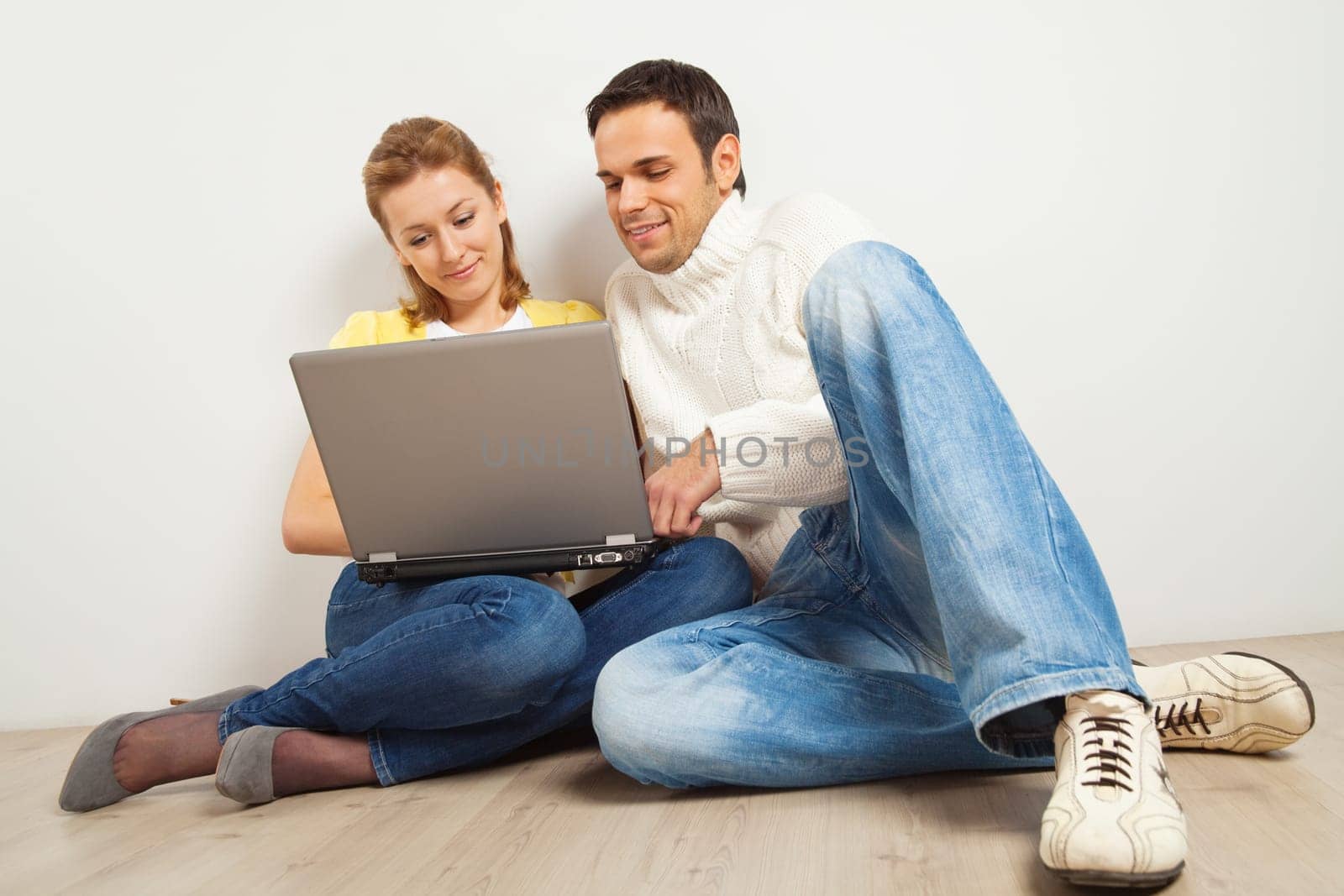 Young happy woman and man sitting together with laptop computer