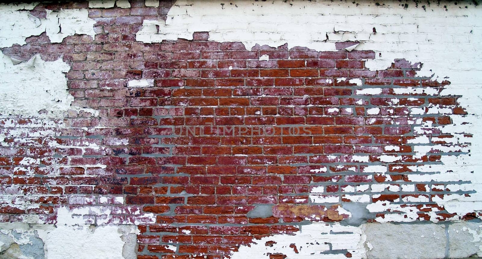 Grungy, weathered brick wall with barred windows, on the back of an old historic building, that has pealing paint and some tuck point renovation done.