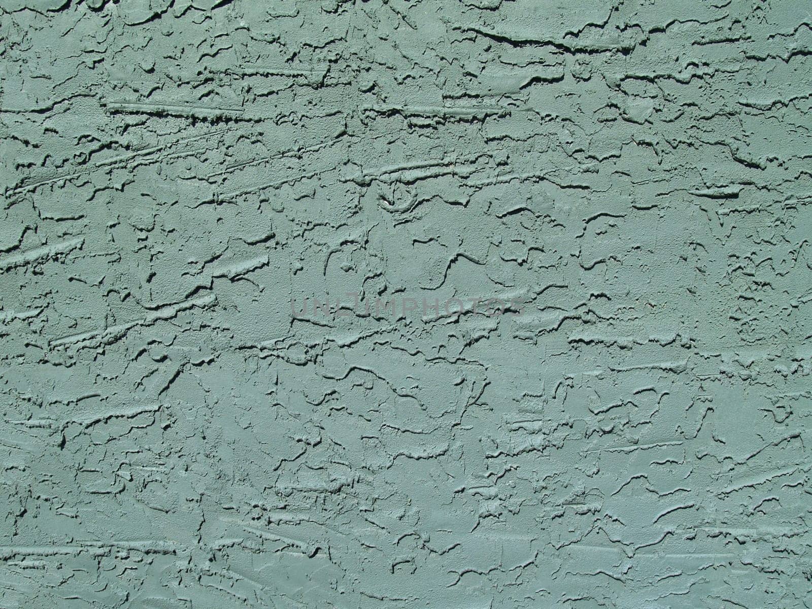 Rough textured concrete or stucco exterior wall painted green.