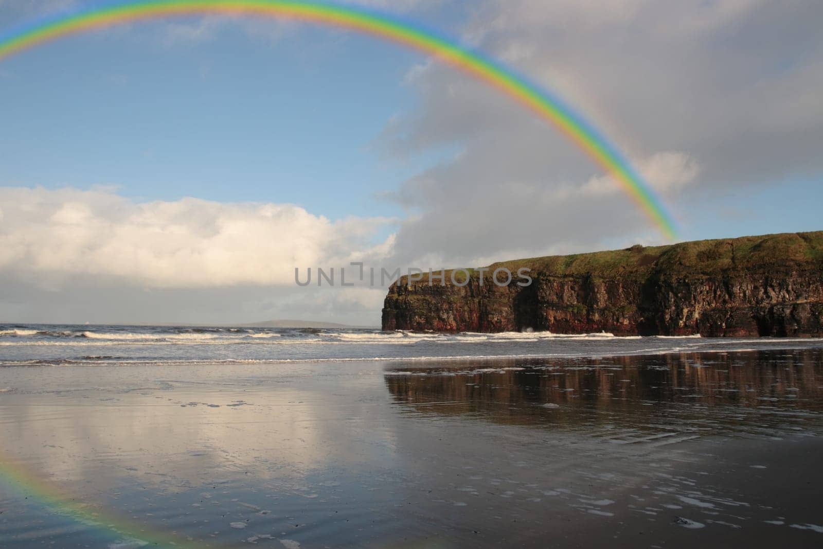 a view of the beach cliffs in ballybunion co kerry ireland with rainbow reflection on a wet stormy day