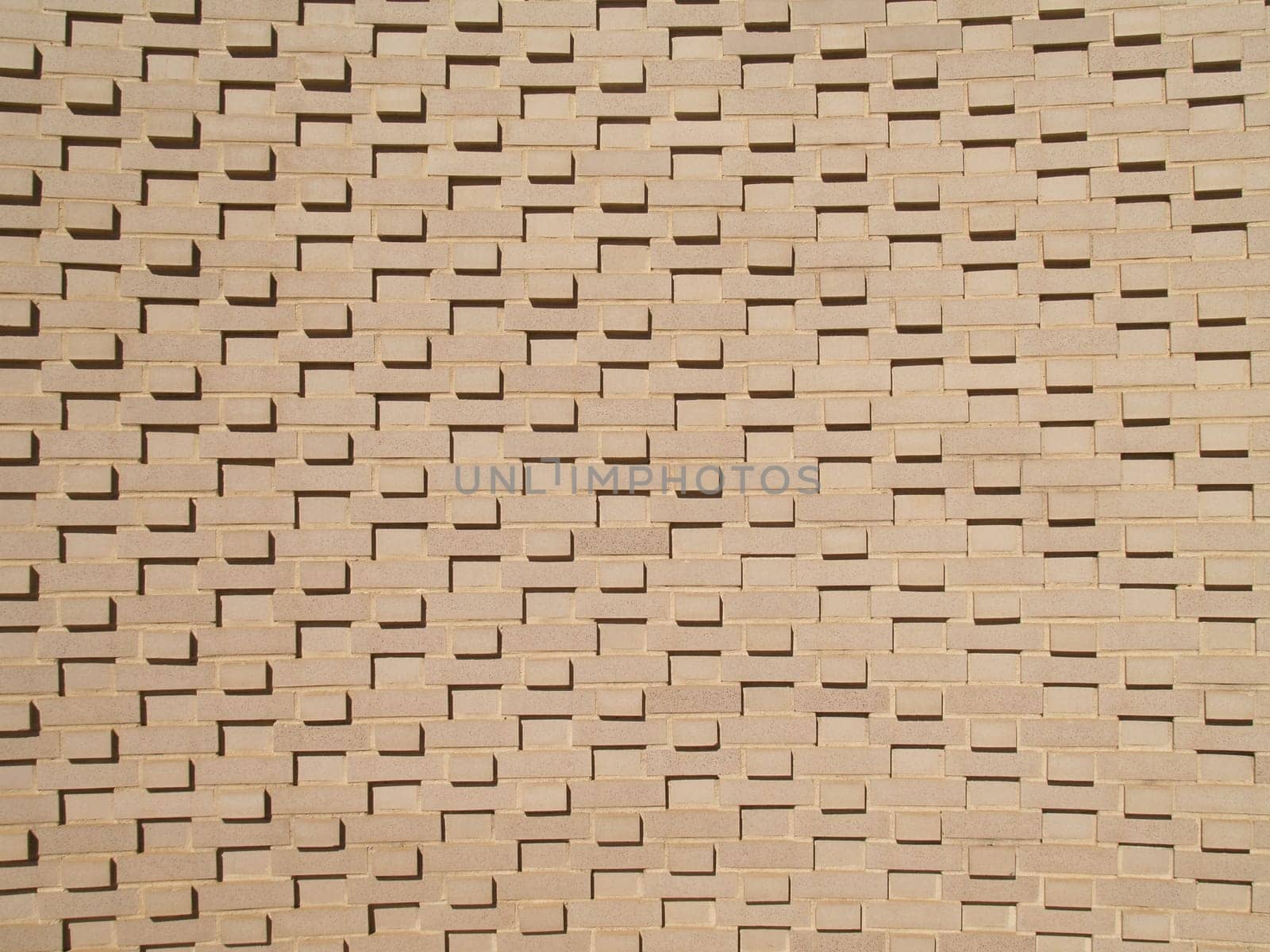 A light colored, beige multi-layered and multi-sized brick wall.