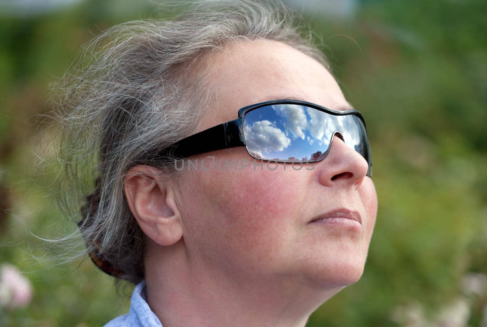 Mature Woman Looking Up To The Sky with Sunglasses