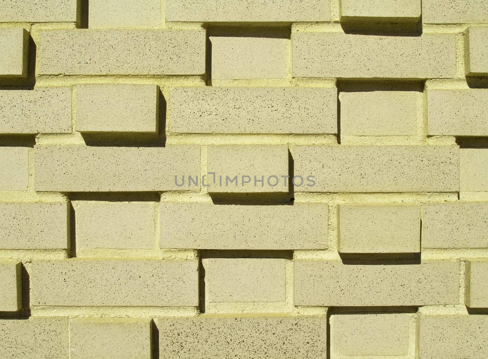 A pastel yellow multi-layered and multi-sized brick wall.