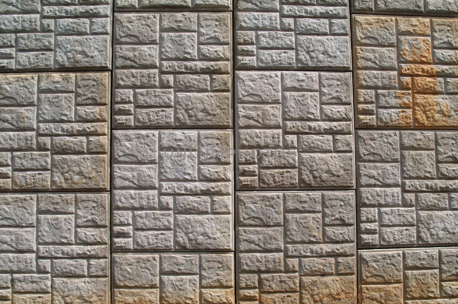 Concrete, weather stained, pressed patterned, retaining wall along a highway.
