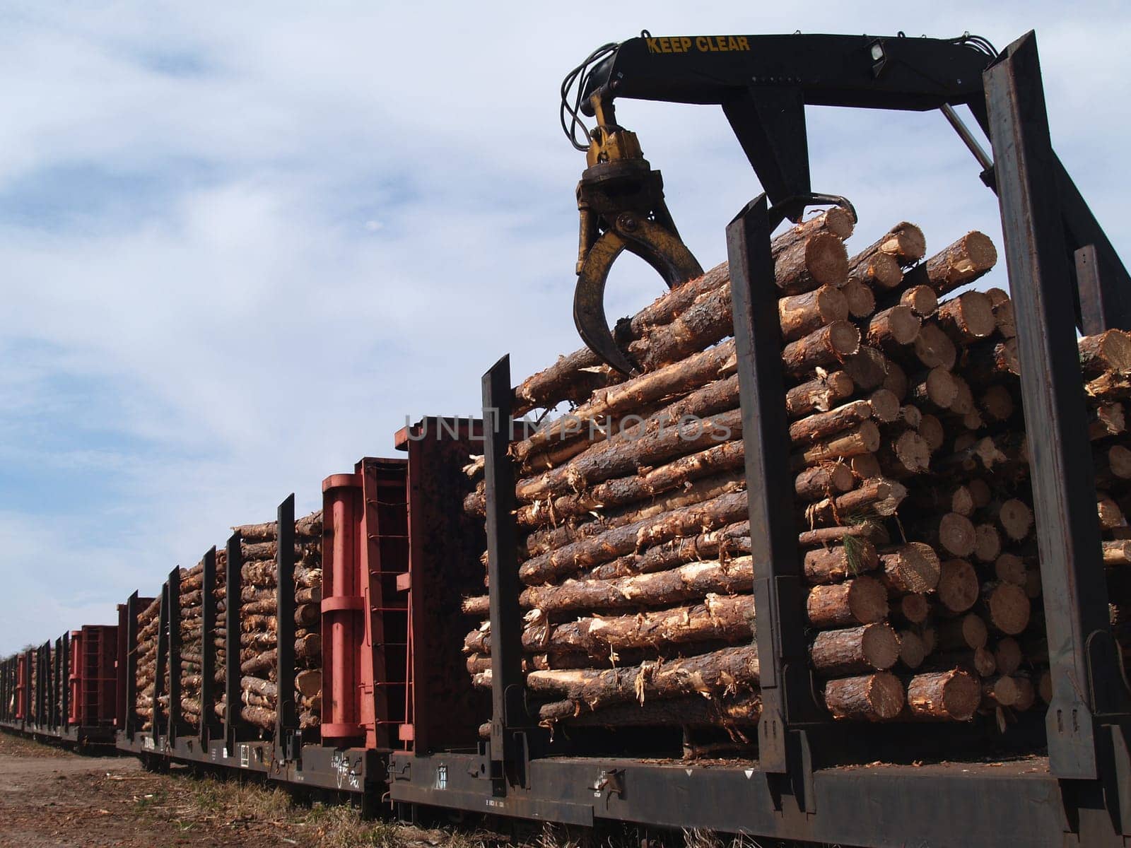 Crane loading cut logs on a railcar.