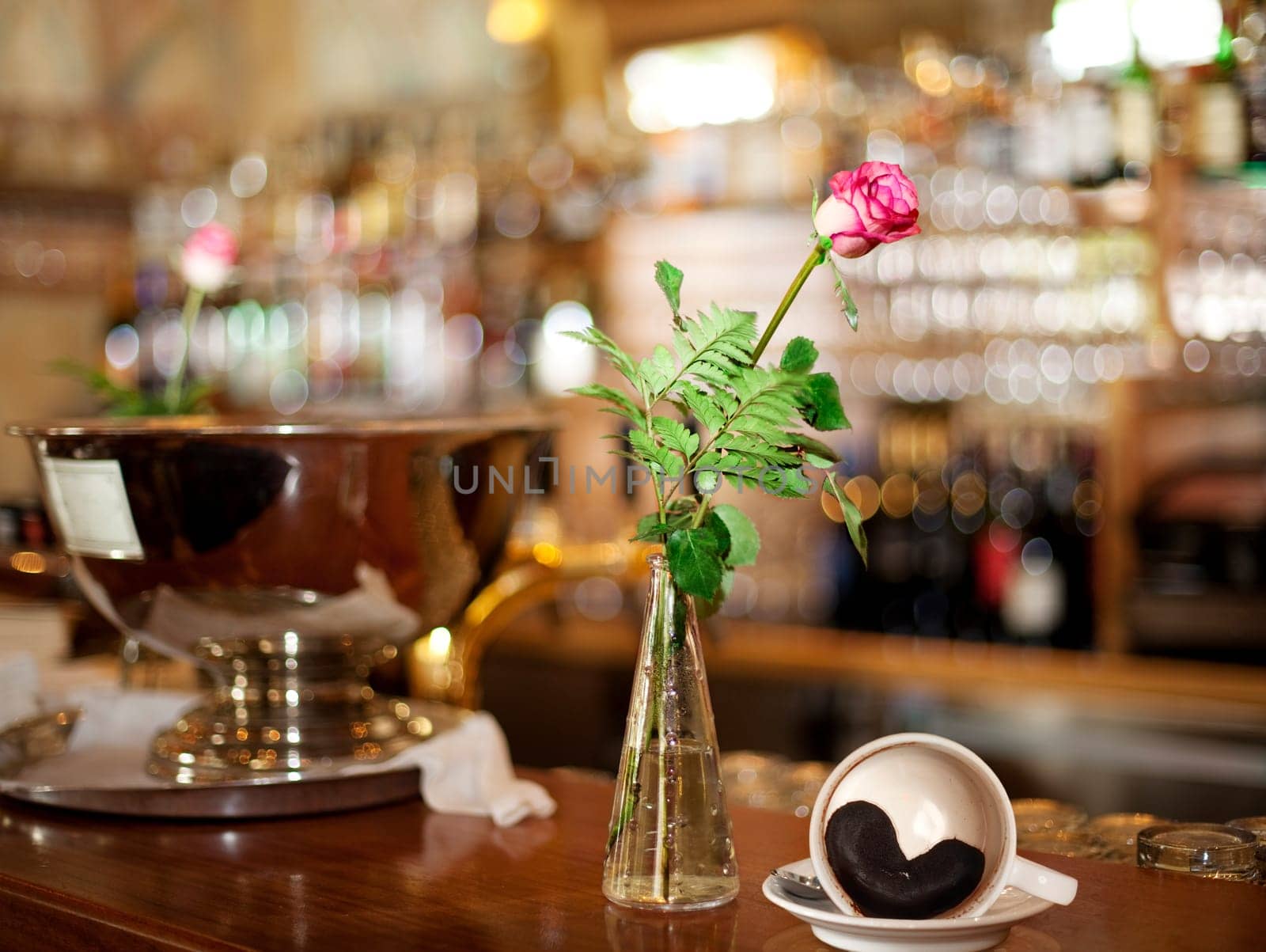 Rose and coffee cup with heart made of coffee grounds at the bar