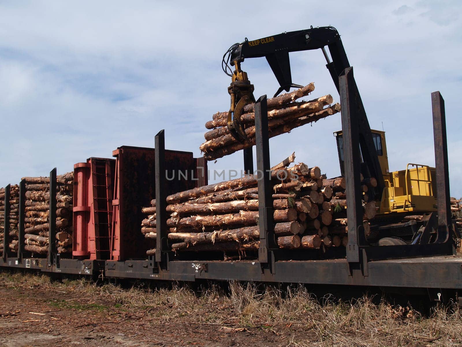 Crane loading cut logs on a railcar.