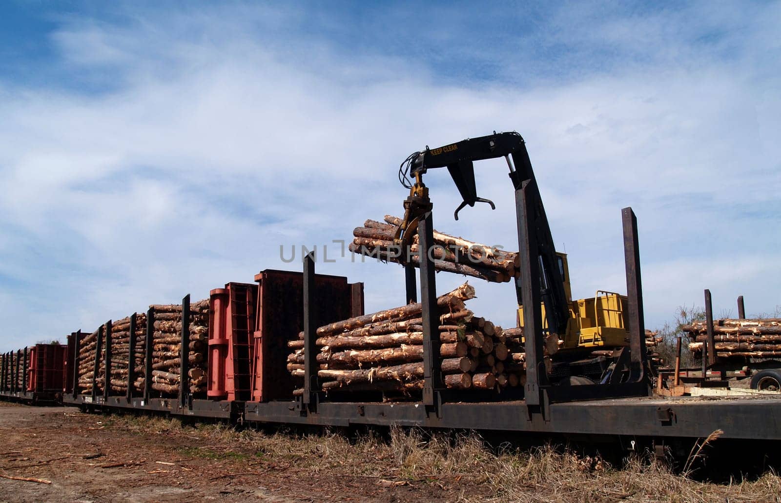 Crane loading cut logs on a railcar.