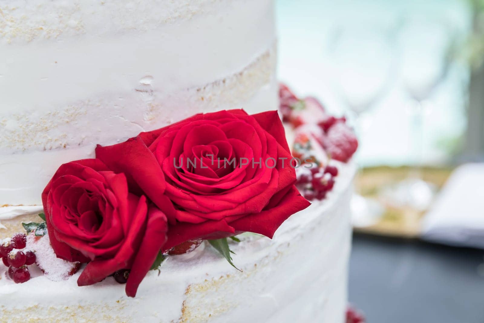 Wedding cake with two beautiful red rose. Wedding reception. Close-up.