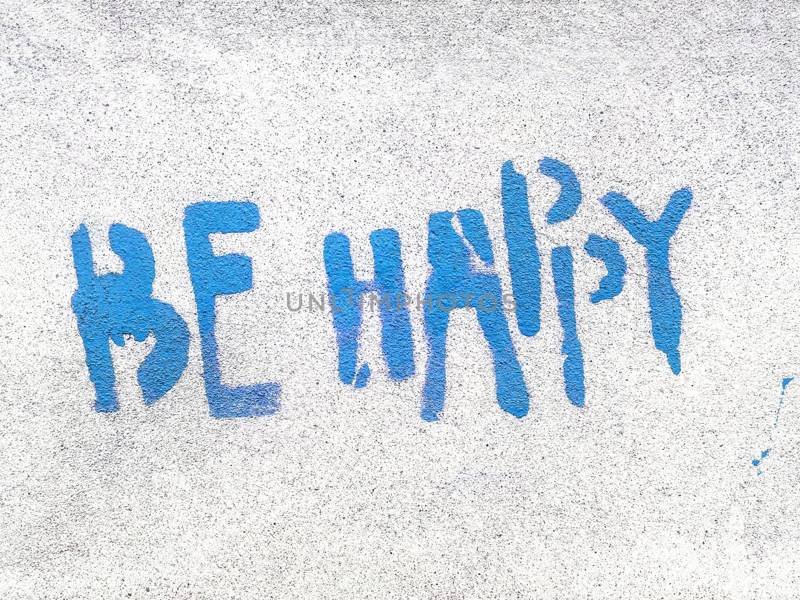 Blue Be Happy written in graffiti style with rough texture isolated on gray background.