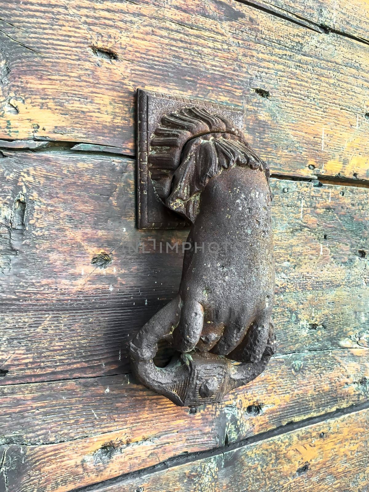 Antique door knocker in an old house, shape of a hand. Wooden door.