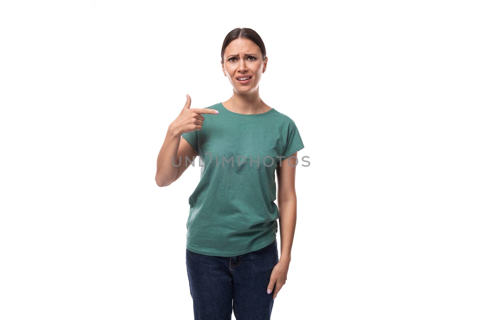 well-groomed young brunette woman dressed in a green t-shirt and jeans looks friendly.