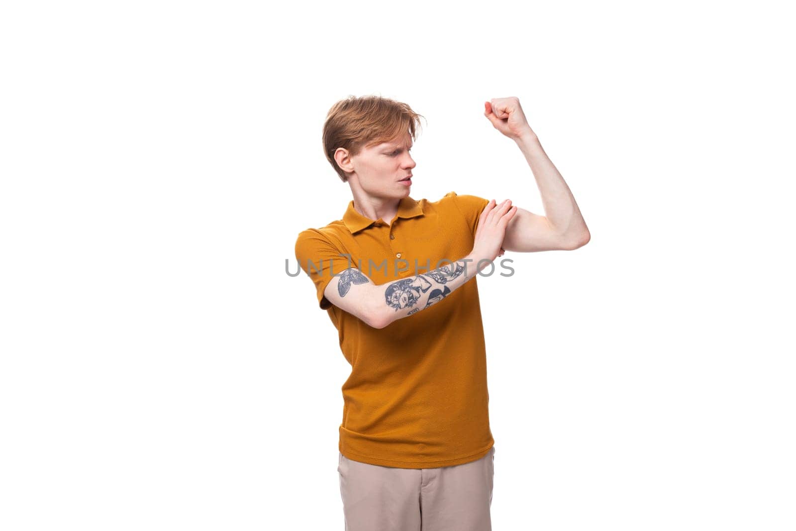 young strong student man with red hair and a tattoo on his arm is wearing a yellow t-shirt.