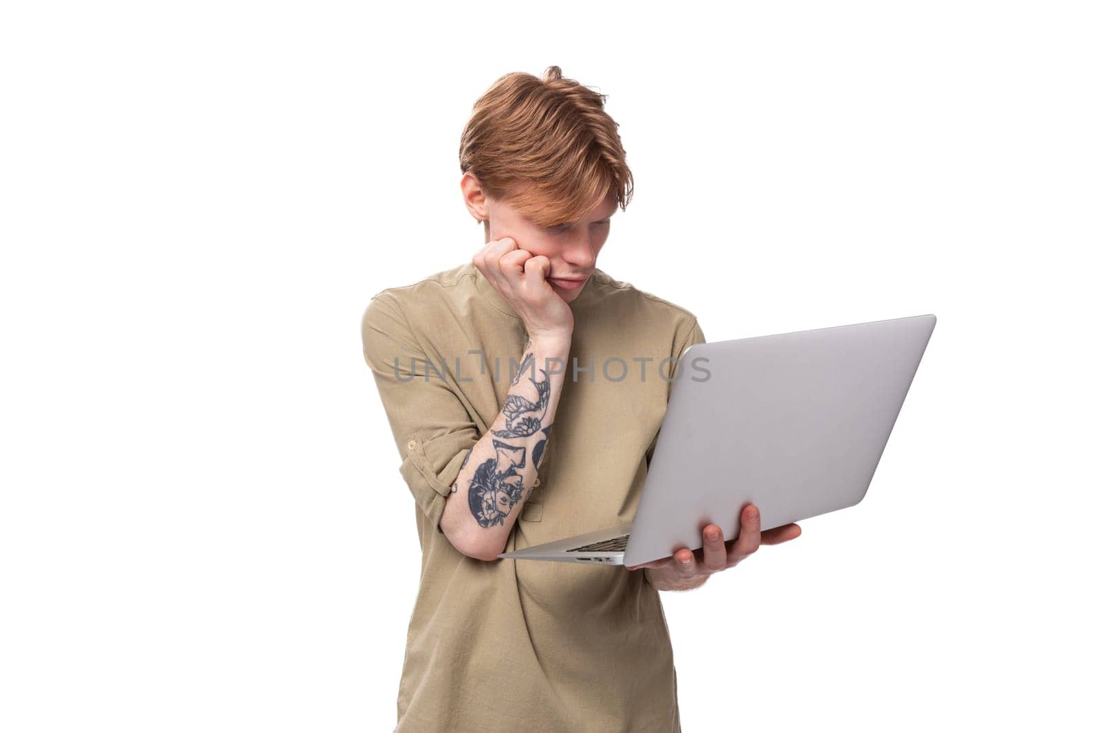 young red-haired man with glasses dressed in a brown shirt uses a laptop for study by TRMK