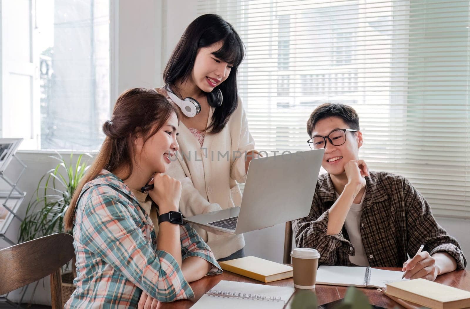 A cheerful and smart Asian woman is standing and sharing his thoughts in a meeting with his team. University students, friendship, startups, teamwork.