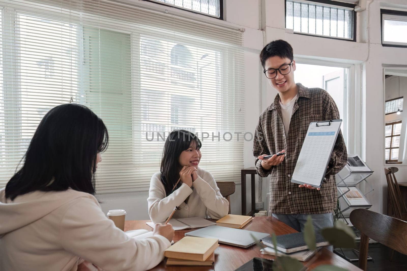 Cheerful young businessman meeting with business people at conference room at office, group of business people working at conference room by wichayada