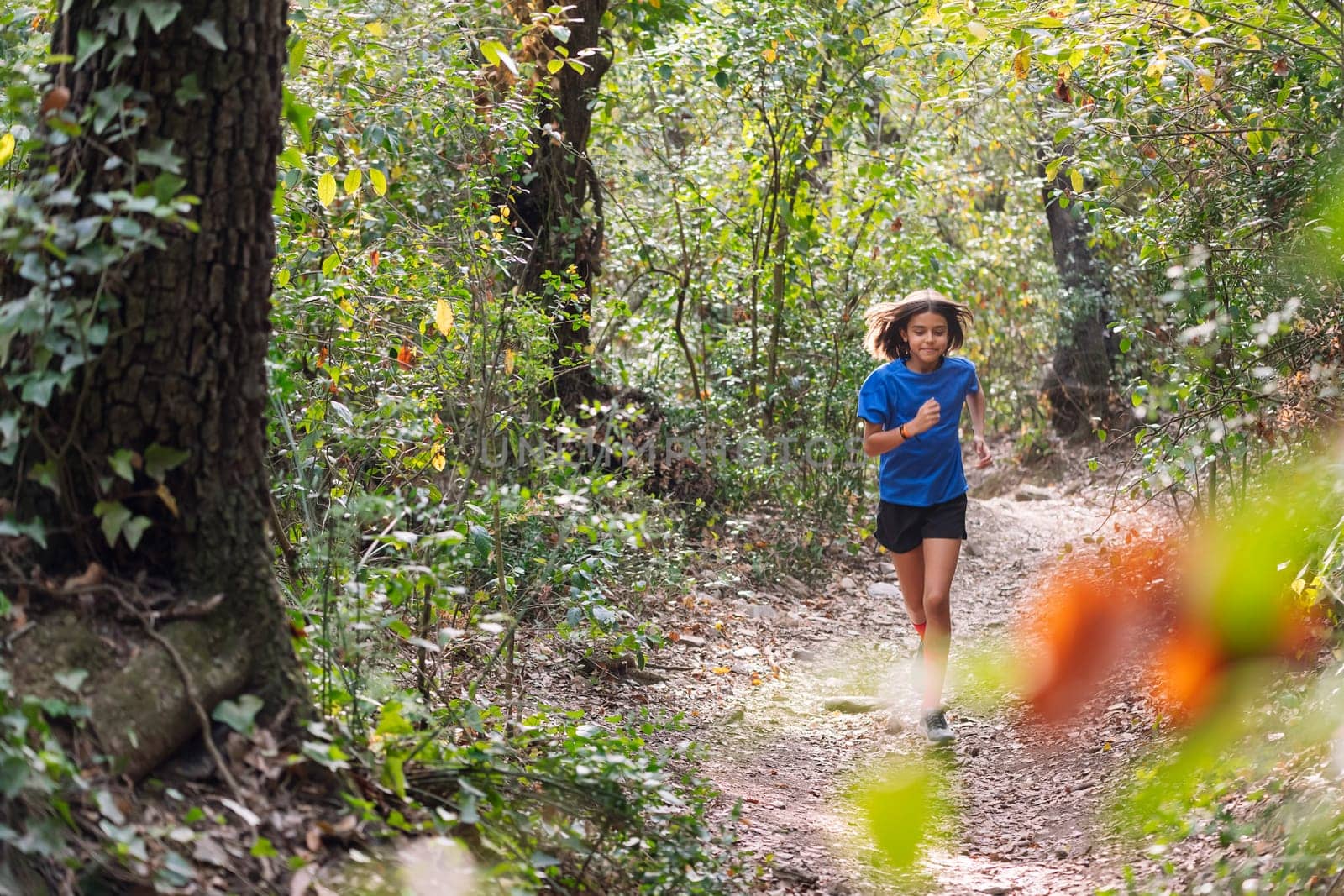 girl practicing trail running in the forest, concept of sport for children in nature and healthy lifestyle, copy space for text