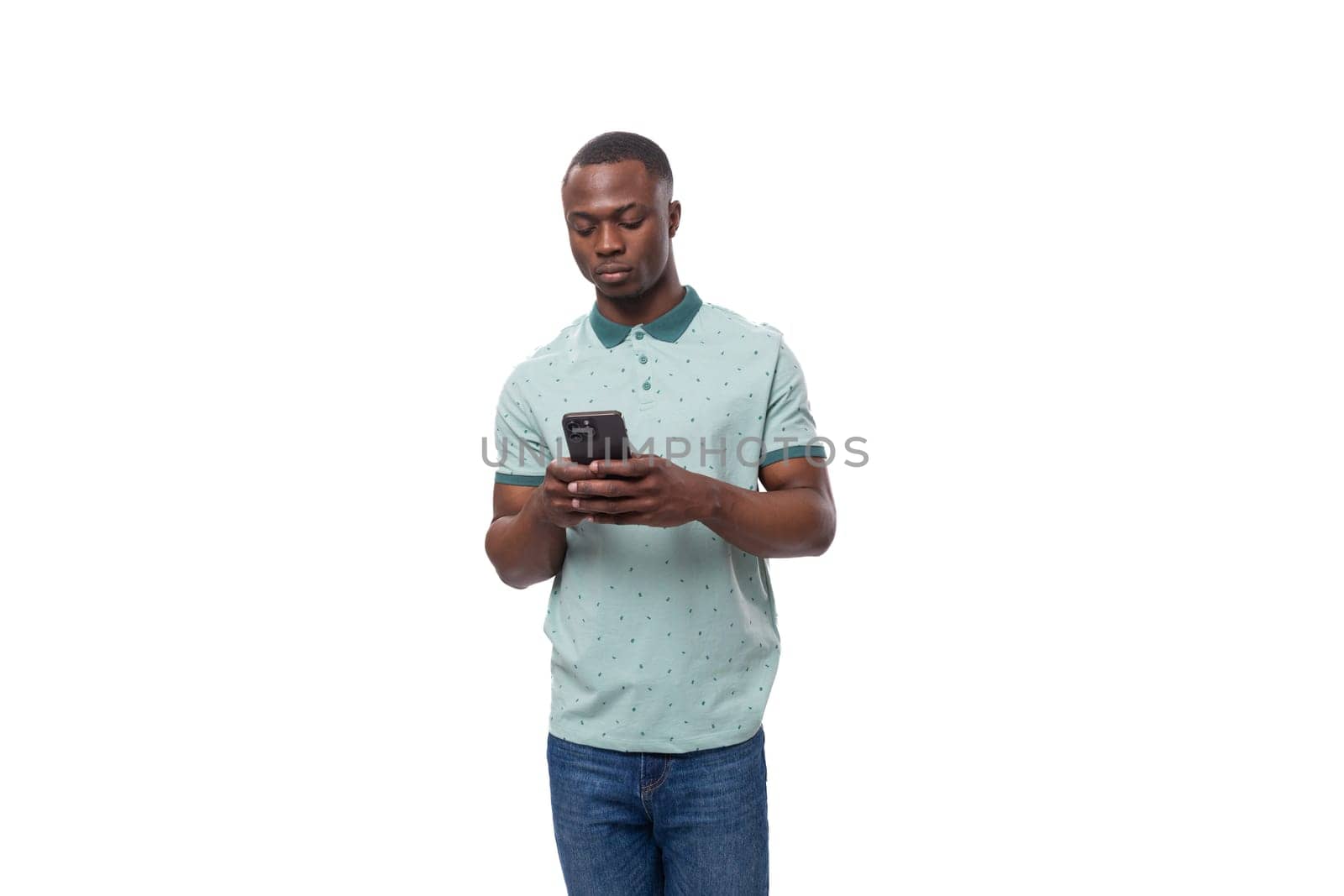 young cute american guy dressed in a mint t-shirt uses a smartphone for social networks by TRMK