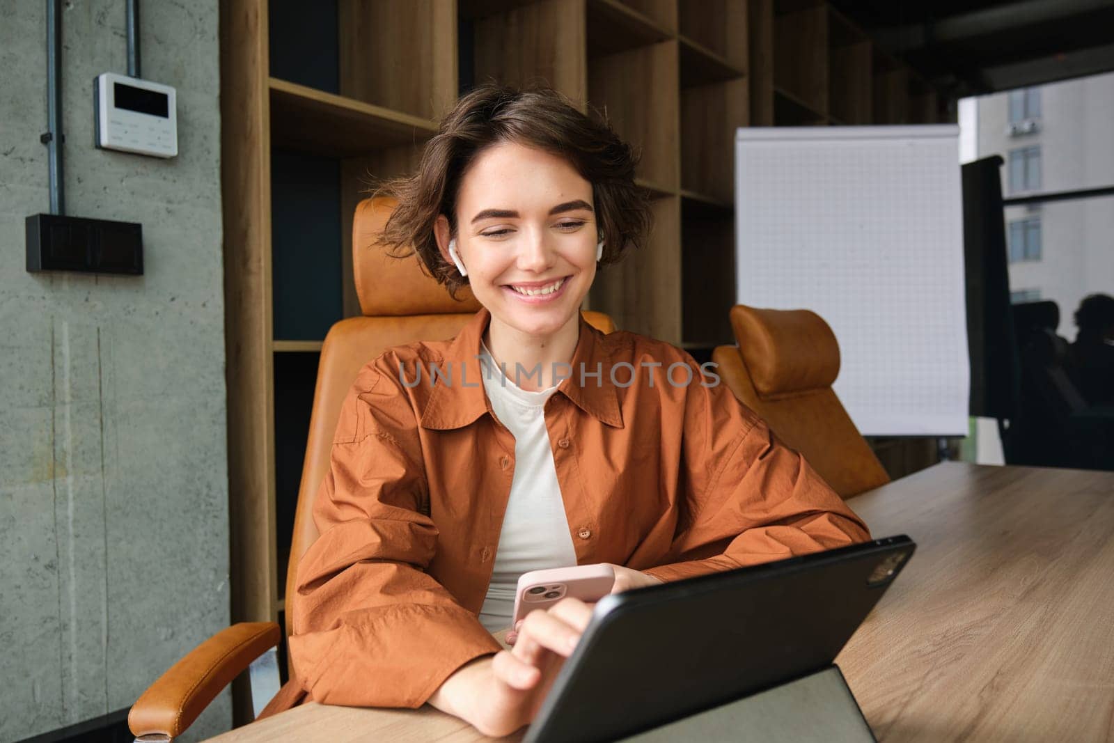 Portrait of woman in office, employee working on project with digital tablet, using device on meeting in conference room.