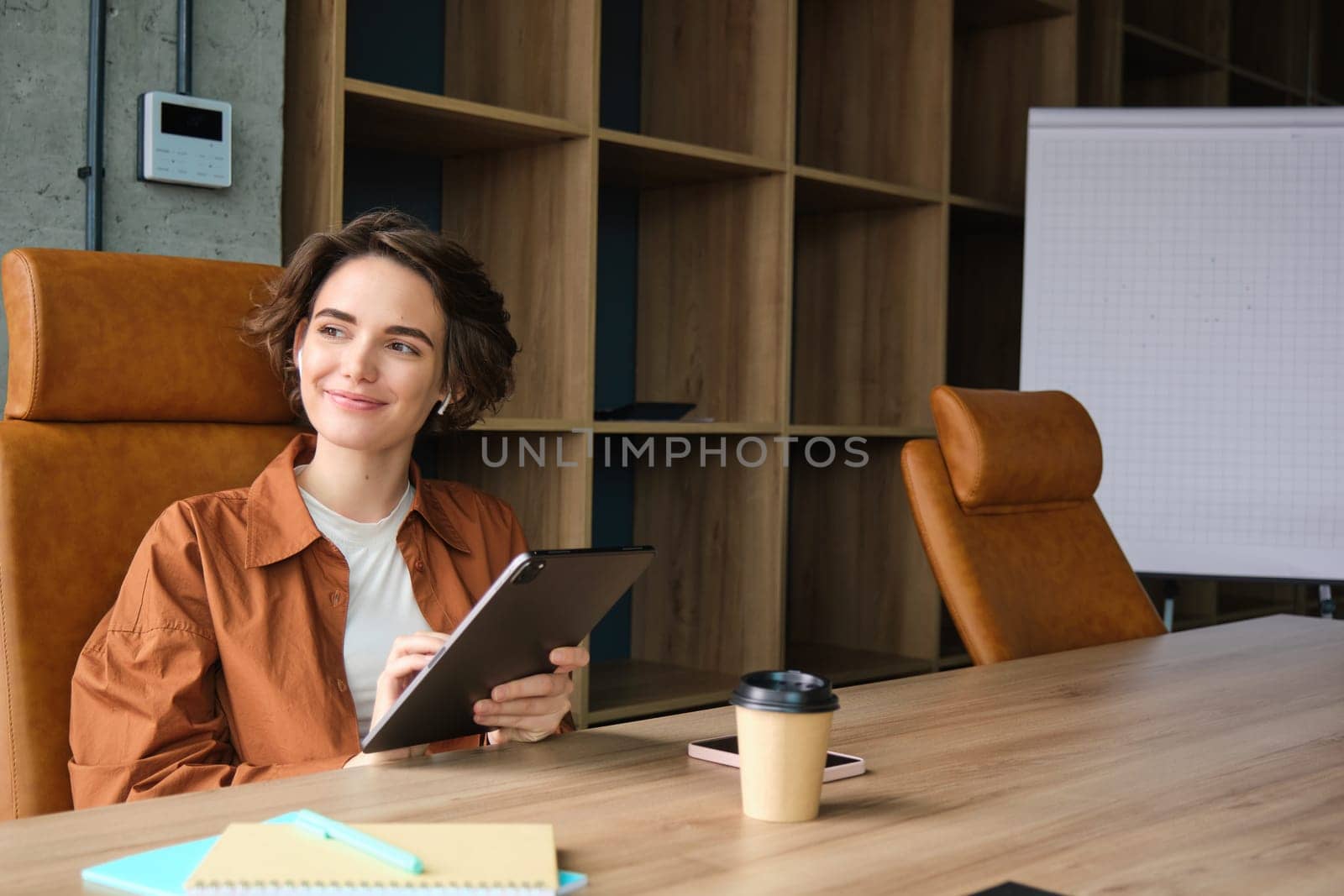 Portrait of happy young businesswoman, saleswoman in casual clothes, working in office, sitting with digital tablet and coffee, working on start-up.