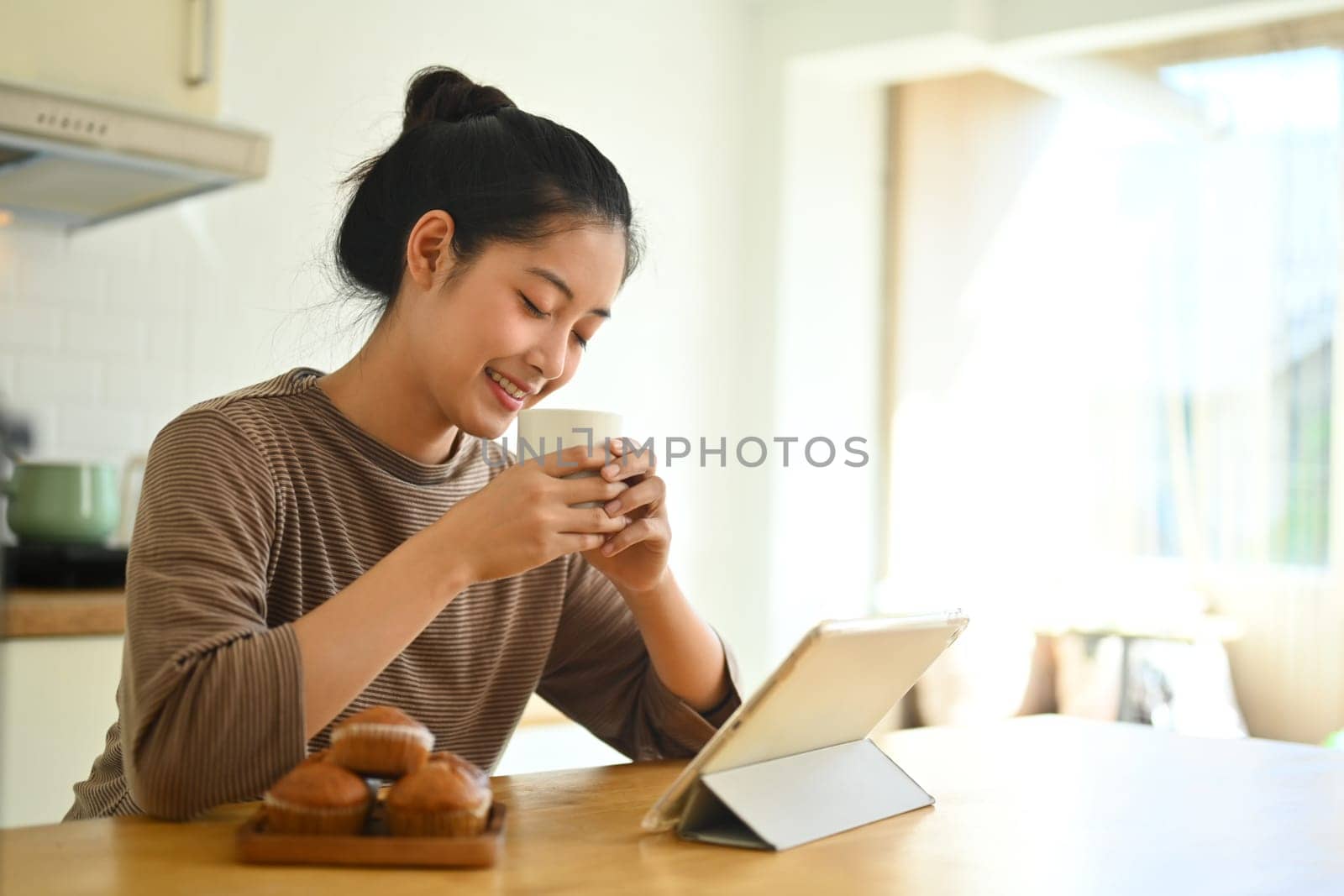 Happy peaceful woman smelling fresh coffee closed eyes and enjoying morning coffee in kitchen.