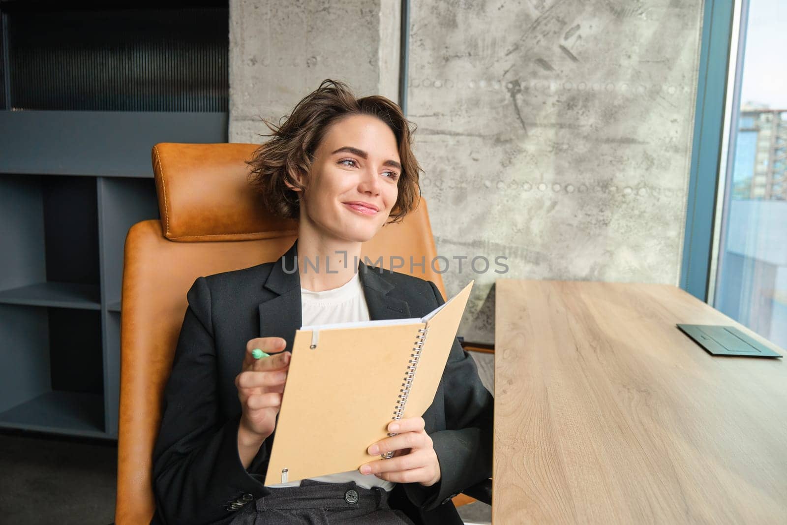 Portrait of woman working in her office. Businesswoman sitting with her notebook, writing and making notes, preparing for presentation or meeting.