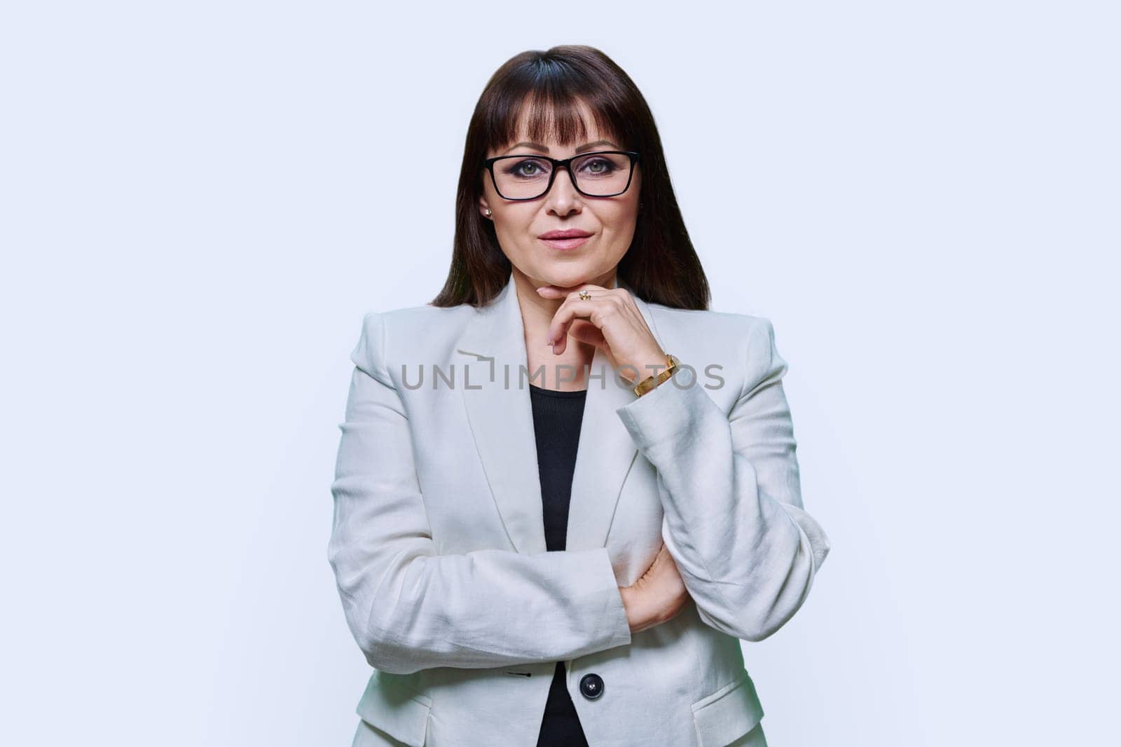 Portrait of serious business confident mature woman in white jacket on light studio background. Business, leadership, management, teaching, finance, insurance, banker, businessperson staff concept