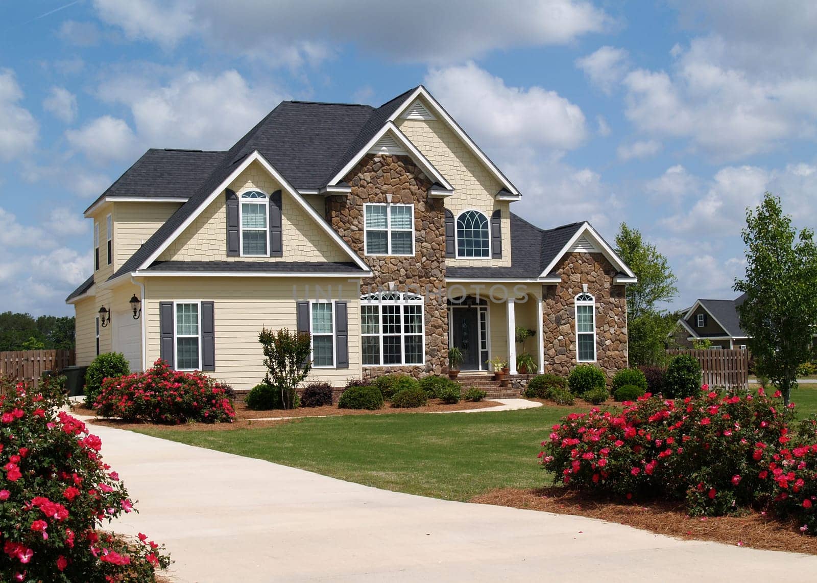 Two story residential home with both stone and board siding on the facade.