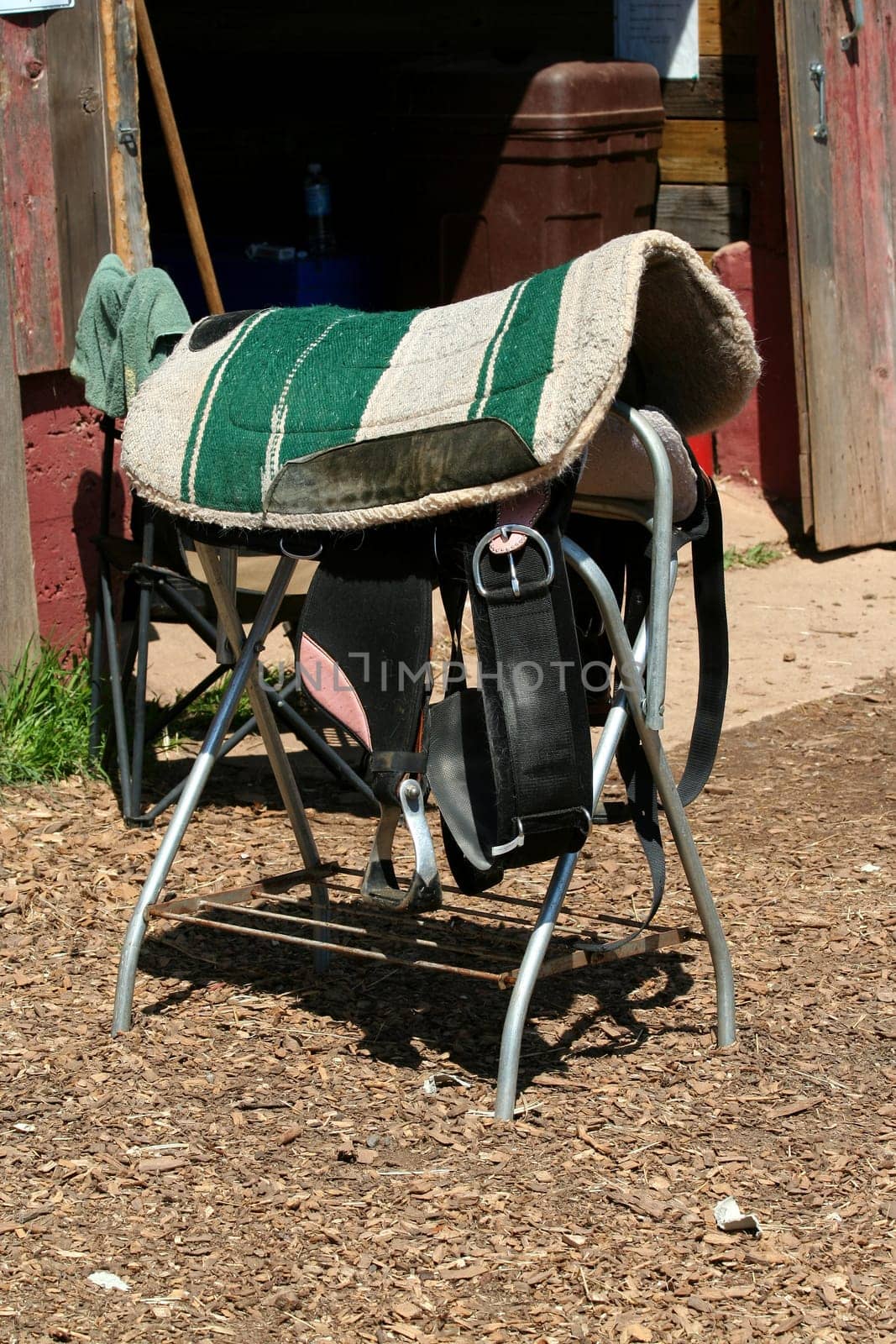 A Bareback saddle on a stand near a barn