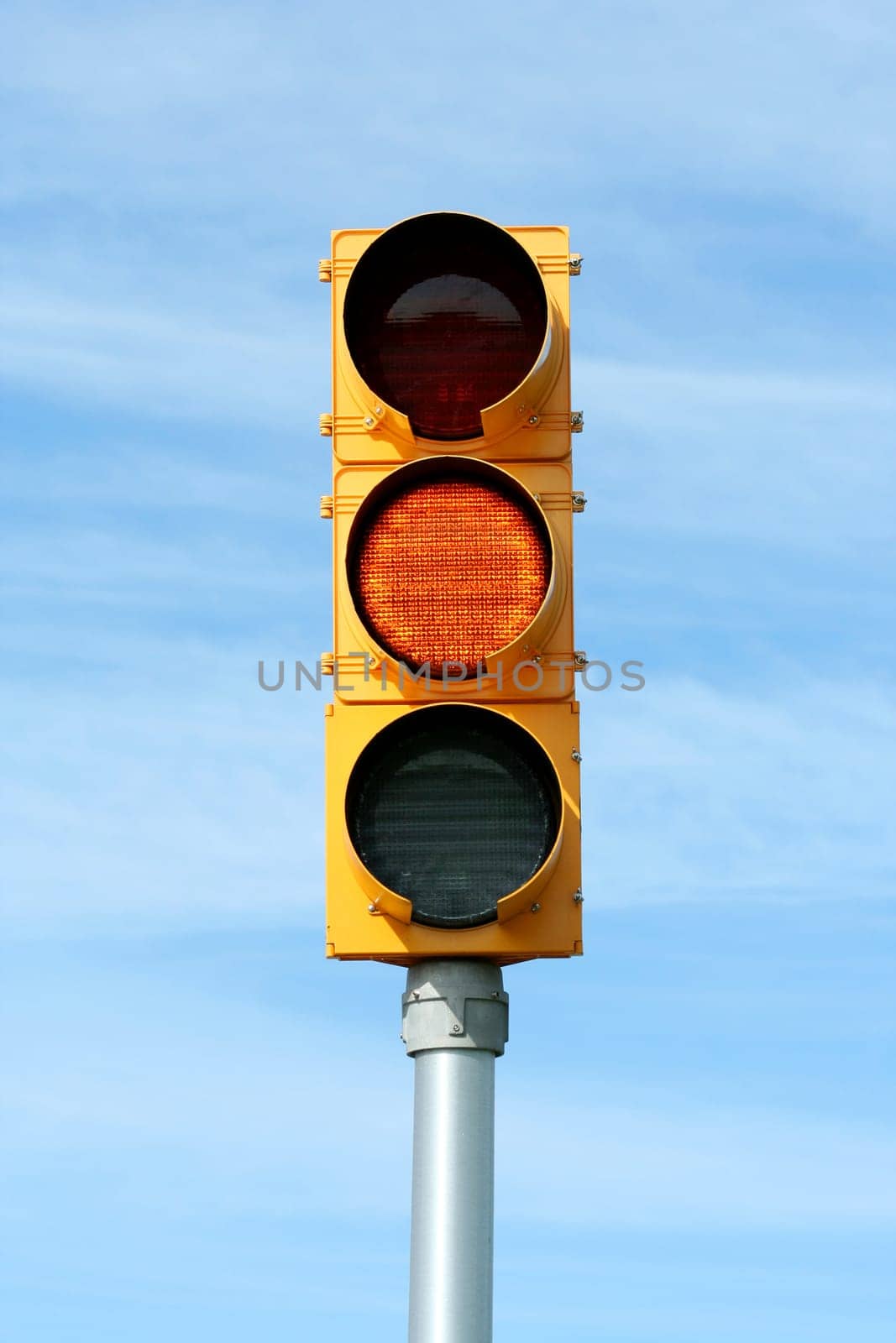 Yellow traffic signal light against blue sky