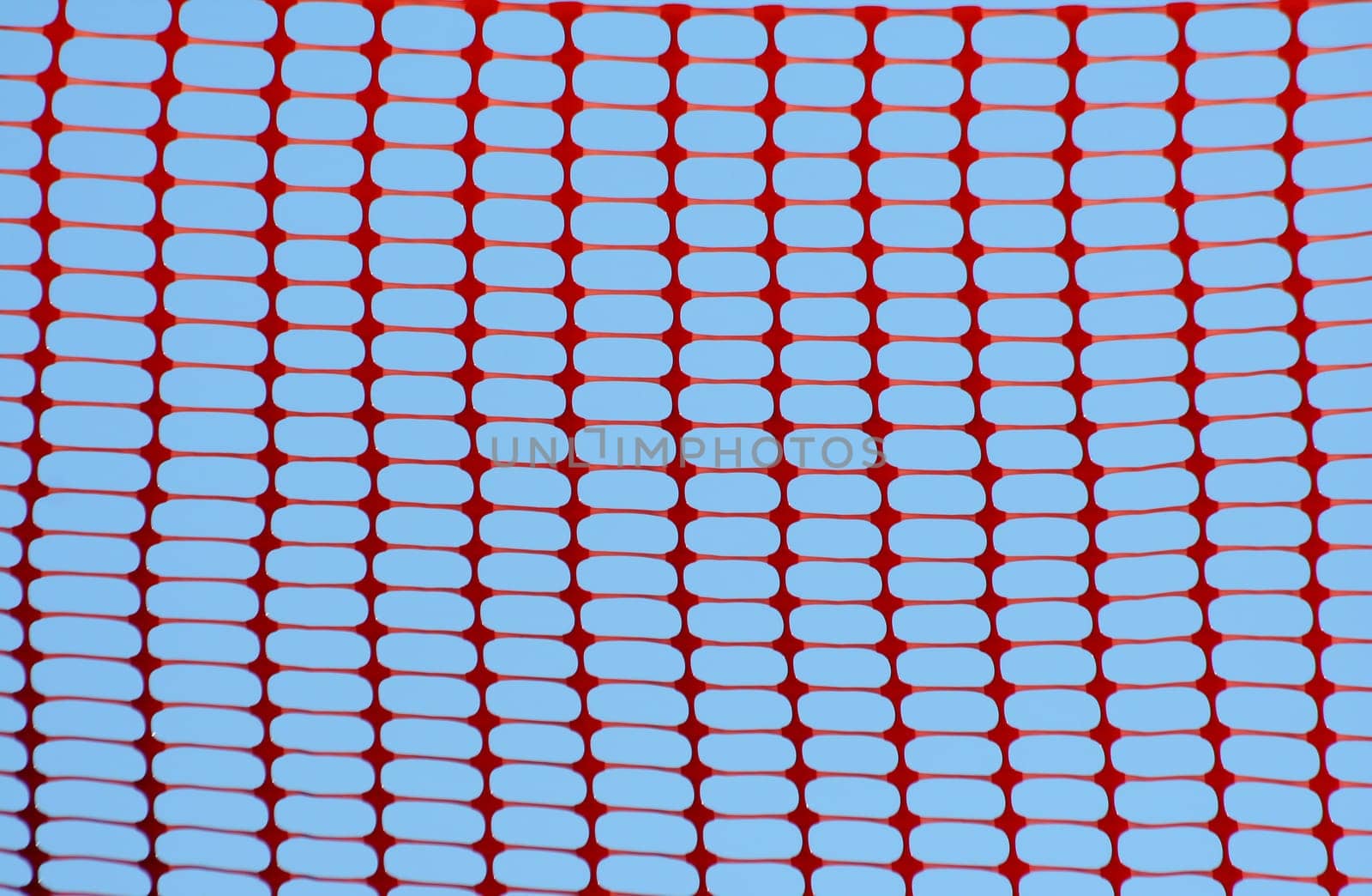 Orange construction fence against blue sky background