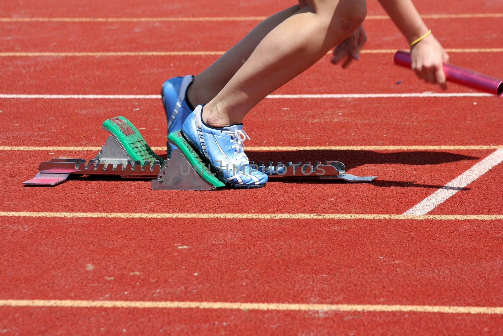 Runner leaving starting blocks with baton